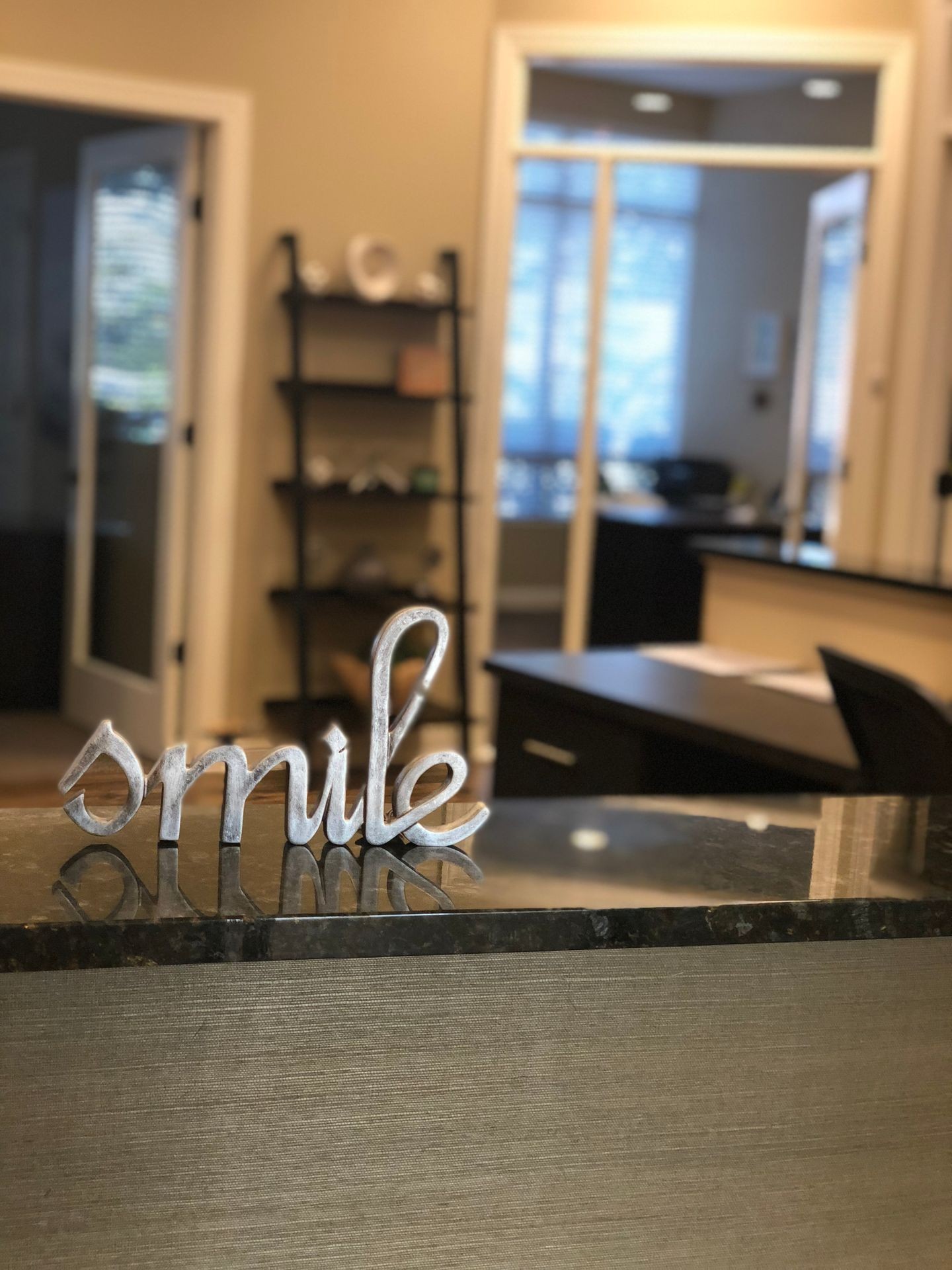 Reception desk with a decorative sign saying 'smile' in a well-lit office area.